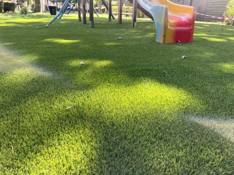 Nahaufnahme von grünem Kunstrasen als Boden auf einem Spielplatz