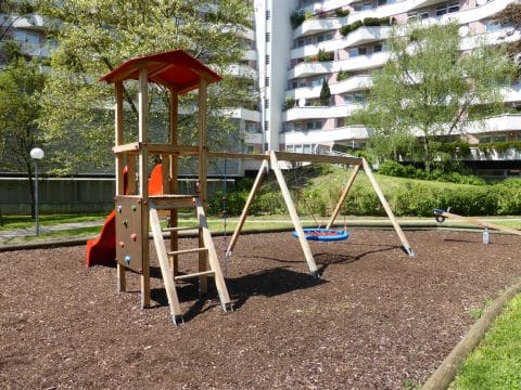 Kinderspielplatz mit Rutschturm und Nestschaukel in Wohnanlage