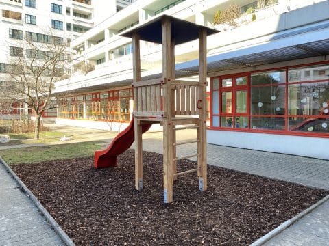 Rutschenturm mit Holzsprossen neben dem Kindergarten