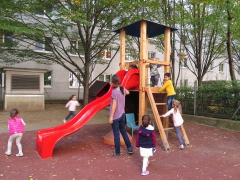 Spielplatz für viele Kinder mit Sprossenwand und roter Rutsche