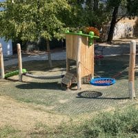 Kinderspielplatz mit Balancierseil, blauer Nestschaukel auf Fallschutz aus Wabenmatten