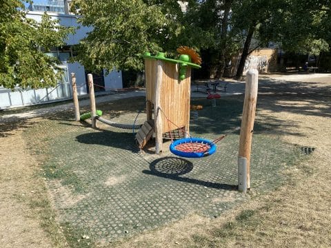 Bunter Spielplatz mit Spielturm Kletterbalken und Schaukel als Nest für Kinder