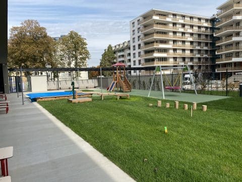 Spielplatz in Wohnanlage mit Nestschaukel Sandkiste und Kletterturm für Kleinkinder und Jugendliche