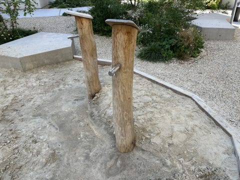 Zwei Wassersäulen aus Holz mit Wassertaster in einer Sandkiste