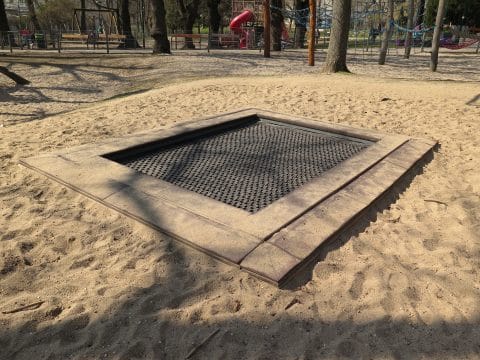 In Boden eingelassenes Trampolin im Sandkasten