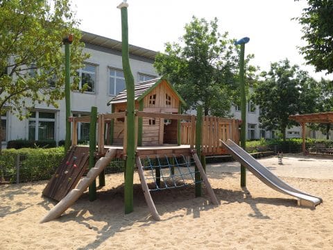 Schönes Spielhaus aus Holz mit Rutsche und Klettermöglichkeiten
