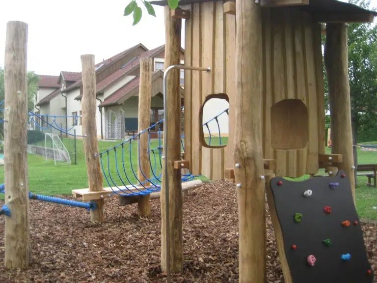 Kletterwand mit bunten Griffen zum Holzhaus auf Stelzen