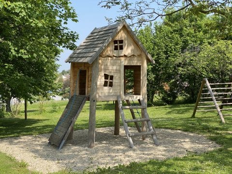 Baumhaus für Kinder auf Wiese auf Stelzen mit Leiter