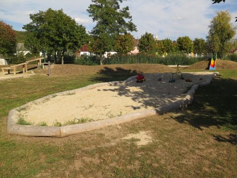 Großer Sandkasten mit Holzeinfassung auf dem Spielplatz