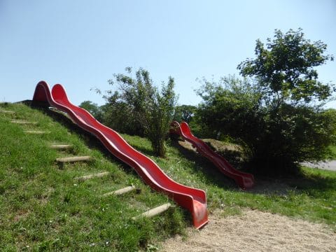 Lange Hangrutsche mit Wellen rot mit Holzstämme als Aufstieg