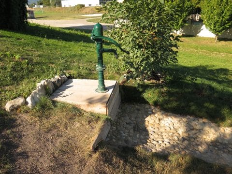 Grüne Wasserpumpe auf Holzpodest montiert