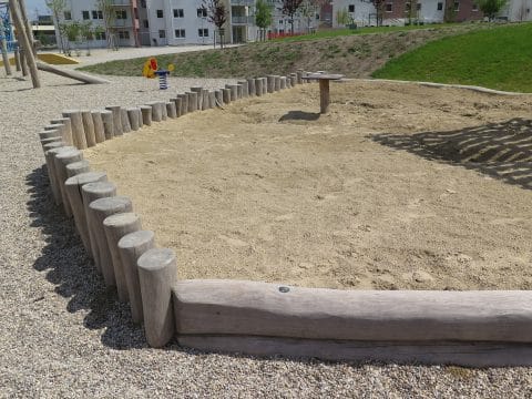 Sandkasten mit Holzpalisaden abgesichert für die Kinder