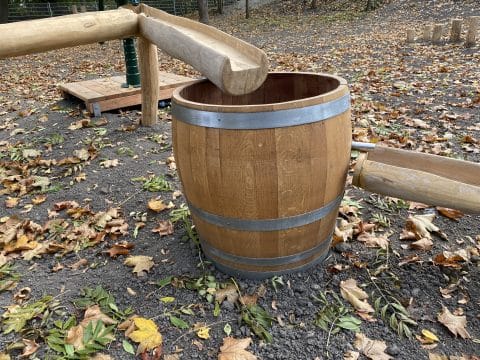Holzfass als Auffangbehälter der Wasserrinne auf Kinderspielplatz