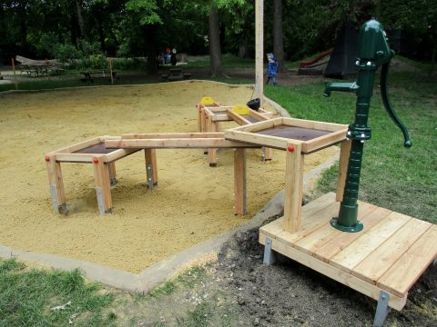 Wasserspielanlage mit Wasserpumpe im Sandkasten auf dem Spielplatz
