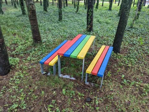 Sitzgruppe ohne Lehne in Regenbogenfarben für Kinder im Wald