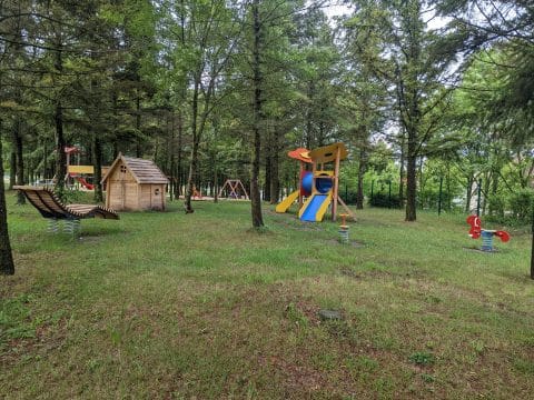 Waldspielplatz mit Spielturm und Rutschen, Holzliege mit Wippen