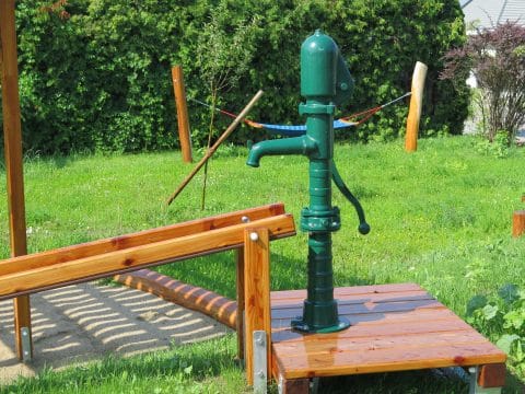 Grüne Wasserpumpe von FREISPIEL auf Holzgestell für Wasserspiele