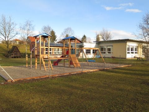 Kindergarten mit großem Spielplatz mit Schaukel und Rutsche