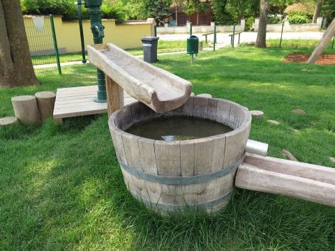 Wasserspiel Holzfass mit Wasser auf der Wiese für Kinder