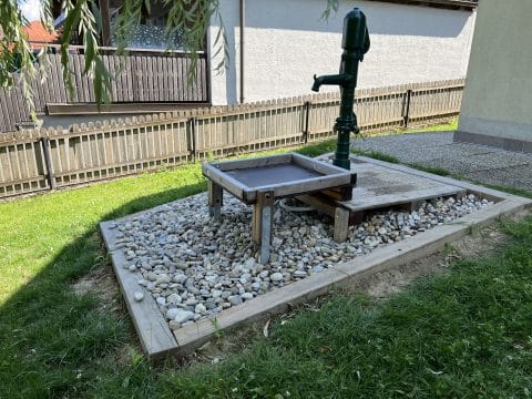 Garten mit Wasserpumpe und Auffangbecken aus Holz
