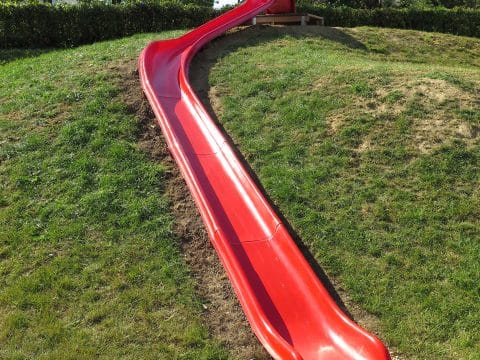Lange rote Rutsche mit Kurve für die Kinder im Kindergarten