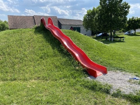 Große rote Hangrutsche auf Spielplatz mit flachem Ausstieg
