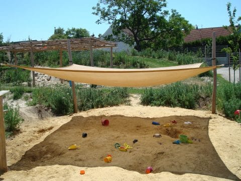 Sonnensegel als Sonnenschutz über dem Sandkasten der Kinder