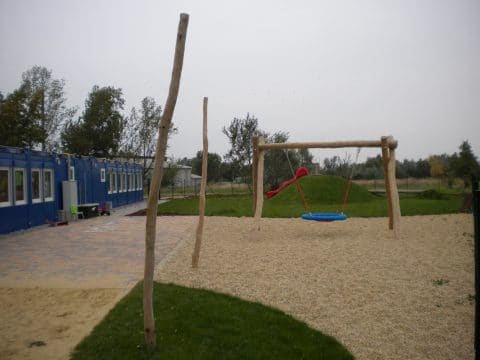 Spielplatz mit Nestschaukel und roter Rutsche für Kinder