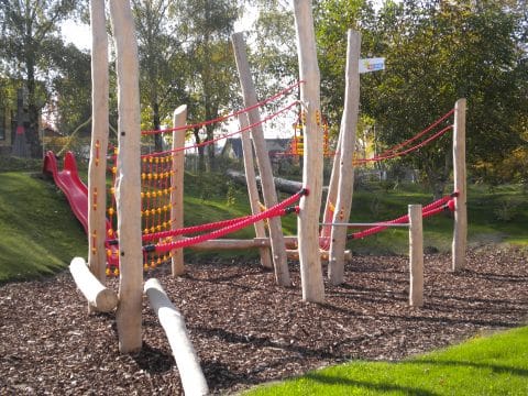 Kletterhindernis-Anlage für Kinder mit viel Holz und roten Seilen