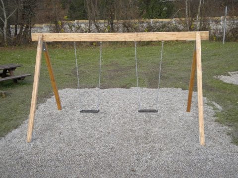 Doppelschaukel mit zwei Brettern auf Kiessand im Park