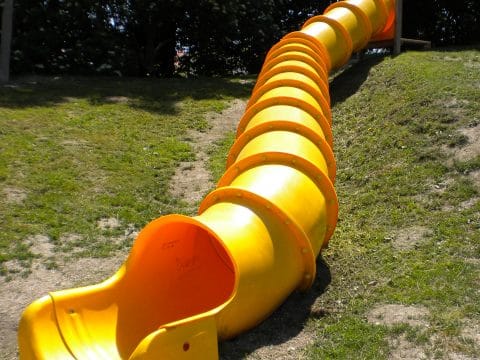 Lange und sichere gelbe Röhrenrutsche am Hang montiert für die Kinder