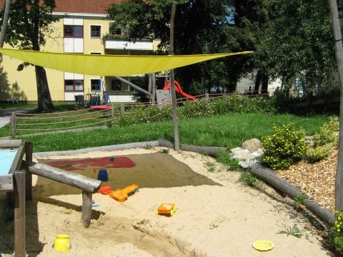 Sandmulde mit Sonnensegel mit Wasserspiele auf dem Spielplatz