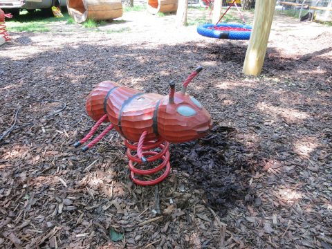 Rote Ameisen-Wippe auf dem Spielplatz auf Rindenmulch
