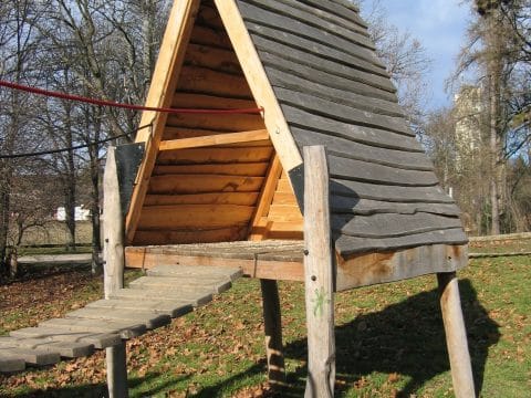 Holz-Spielhäuschen mit Wackelbrücke im Park