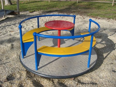 Buntes Karussell am Kinderspielplatz mit Sitzbank