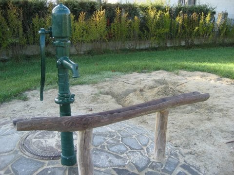 Wasserpumpe mit Wasserlauf aus Holz in einen Sandkasten
