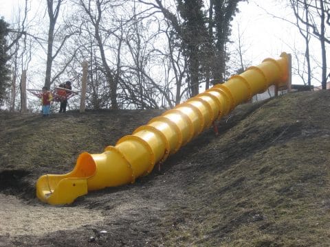 Lange Röhrenrutsche in gelb auf einem Podest auf dem Hügel