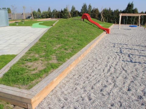 Spielplatz mit Fallschutz-Kies und toller Holzumrandung als Sitzfläche