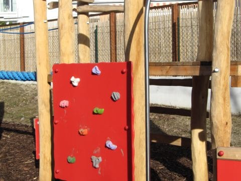 Kletterwand mit bunten Haltegriffen am Kinderspielplatz