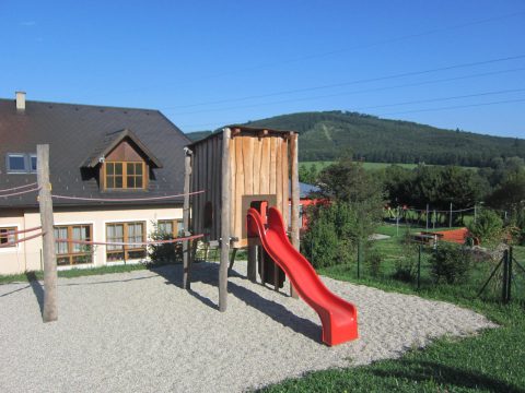 Spielkombination mit Holzhaus auf Stelzen mit einer Rutsche