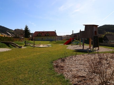 Schön angelegter Spielplatz mit Baumhaus, Sandkiste und Breitrutsche