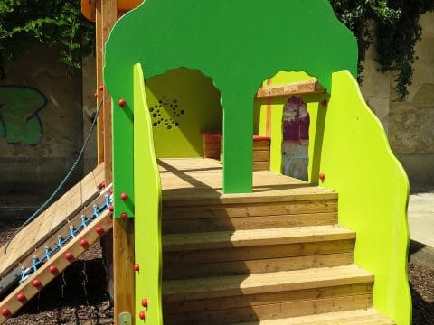 Spielanlage in Grün mit Treppenaufgang für Kleinkinder