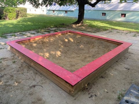 Sandkiste mit roten HDPE Platten im Park für Kinder
