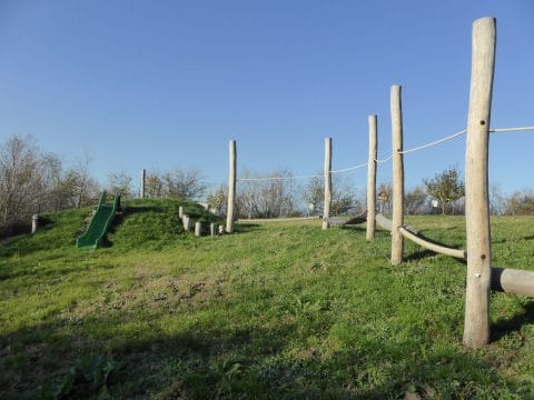 Spielplatz mit langer Balancierstrecke und grüner Rutsche für Kinder