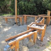 Wasserspielplatz aus Holz mit Wasserrad in den Sandkasten