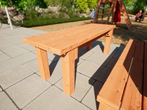 Tisch aus Holz in Kindergröße vor einem Spielplatz